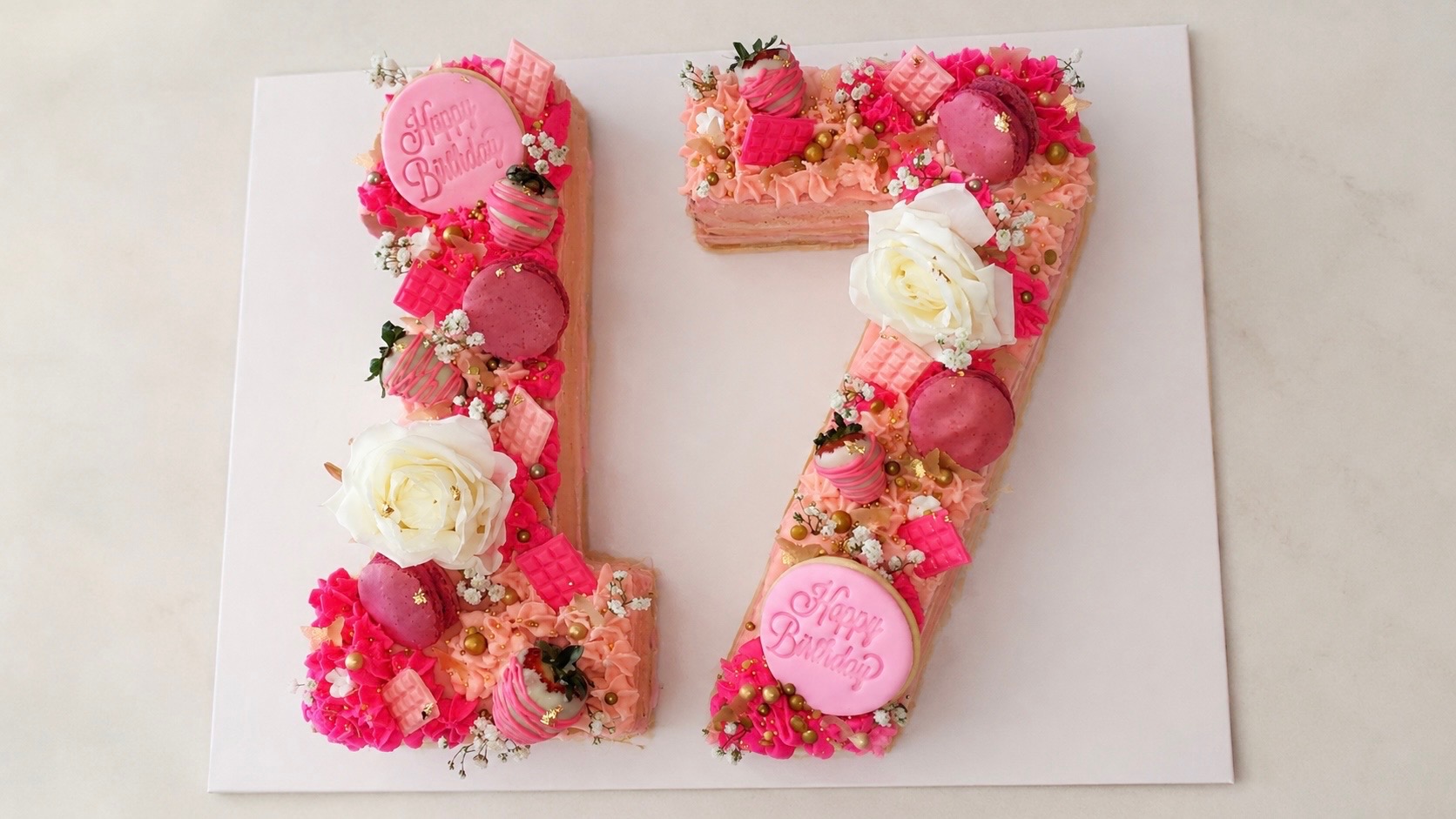 Pink number 17 birthday cake with macarons, roses and gold accents